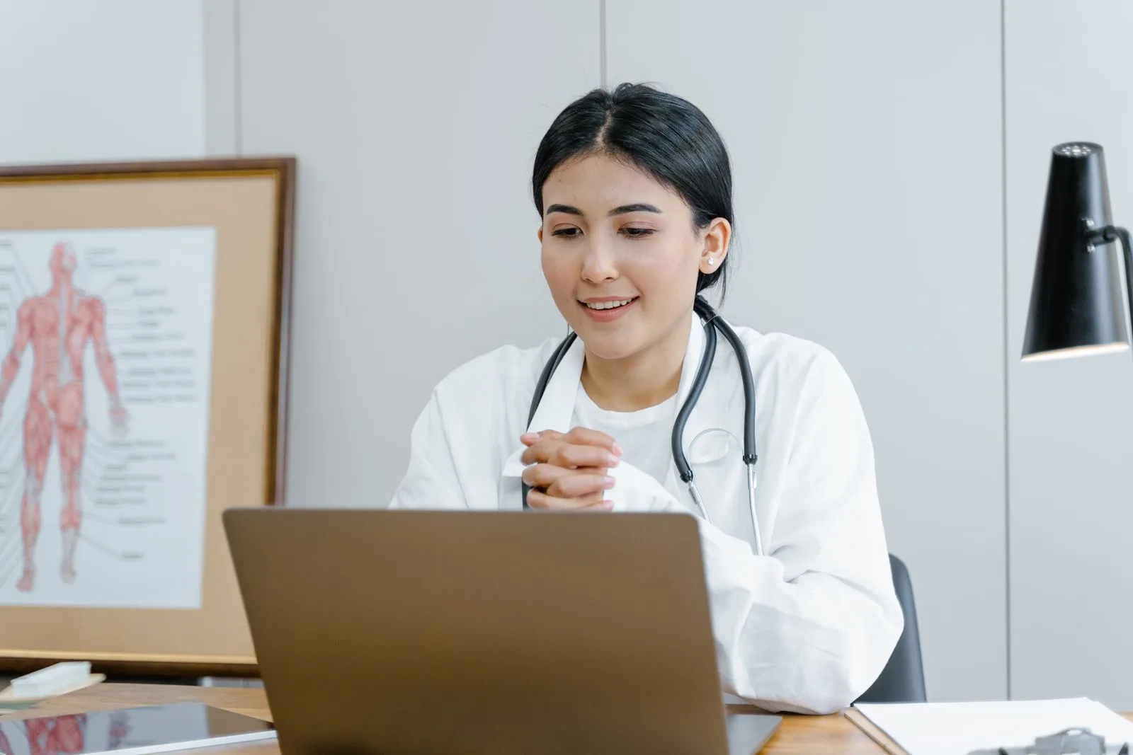 A clinician working at a laptop in a medical office.