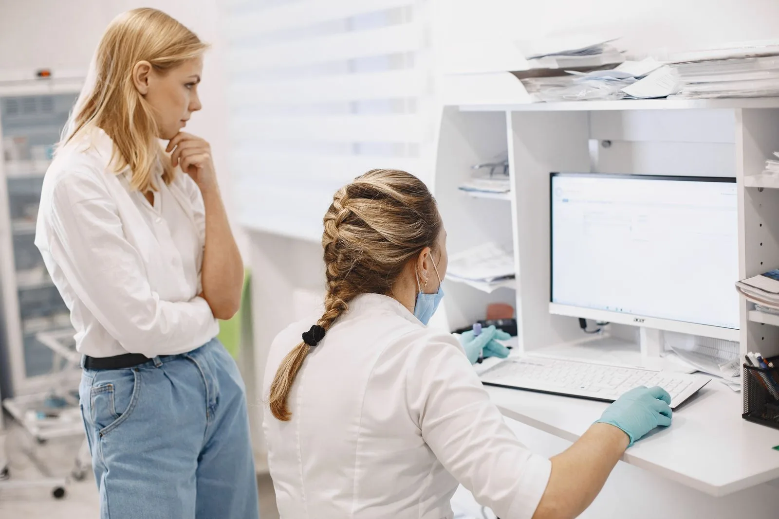 A clinician and colleague reviewing information on a desktop monitor.