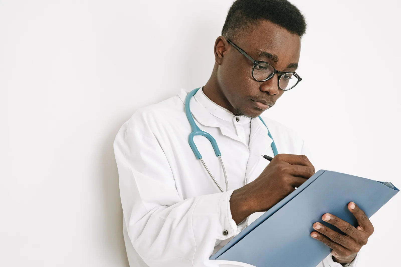 A clinician reviewing a blue folder and writing notes.